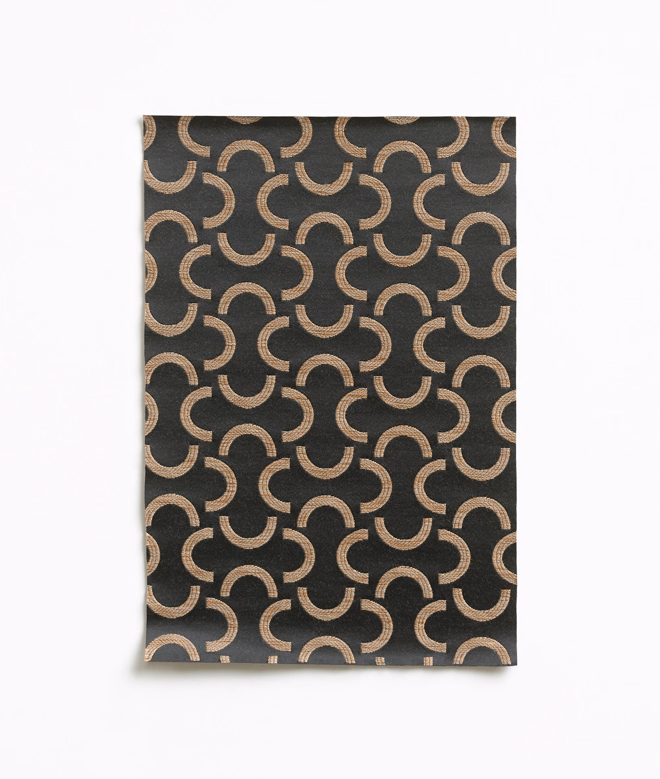 Charcoal textile with repeating bronze crescent arcs and a subtly lustrous woven surface