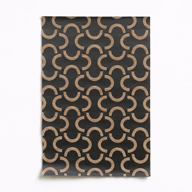 Charcoal textile with repeating bronze crescent arcs and a subtly lustrous woven surface