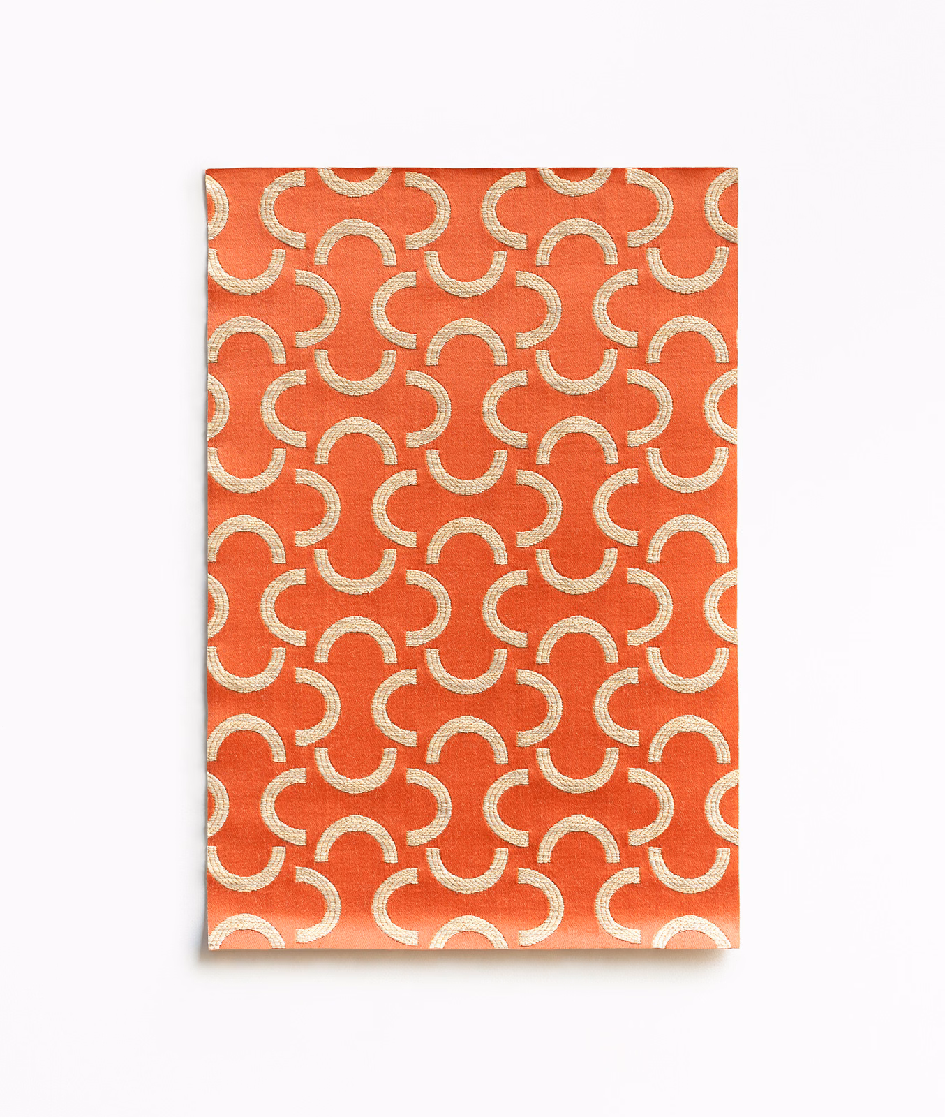 Warm coral satin with repeating cream arc motifs and a soft surface sheen