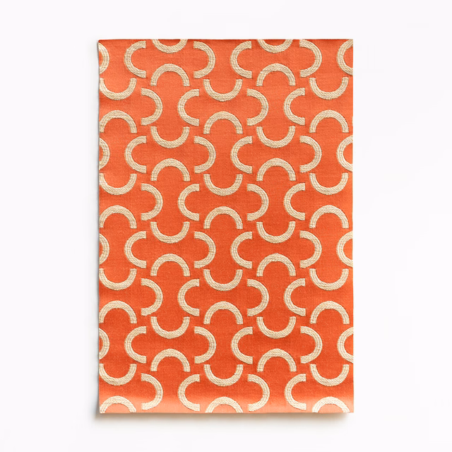 Warm coral satin with repeating cream arc motifs and a soft surface sheen