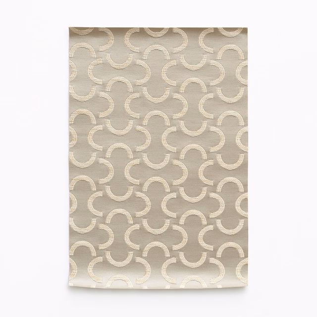 Warm taupe satin with cream interlocking curved motifs and subtle sheen