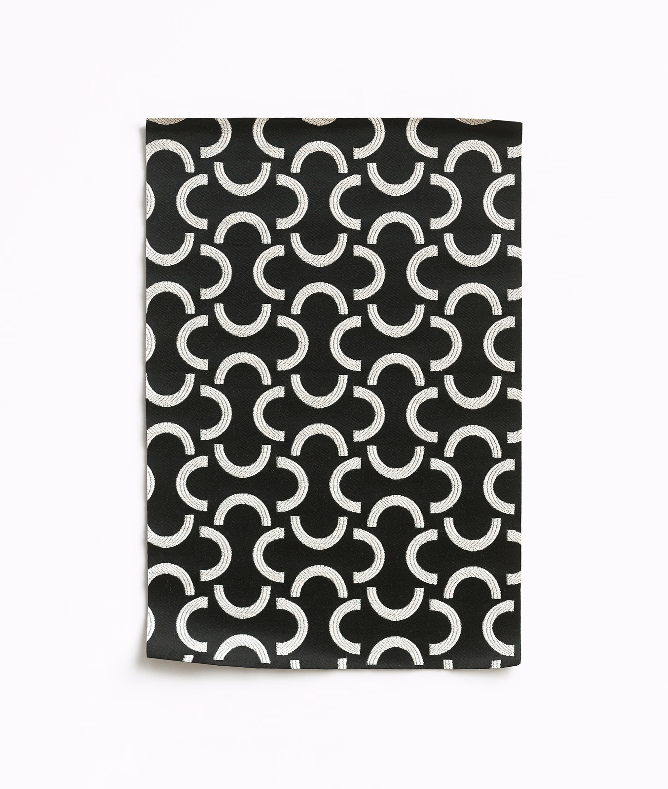 Black woven swatch with repeating ivory crescent and horseshoe motifs