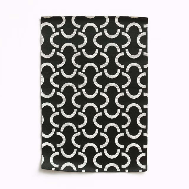 Black woven swatch with repeating ivory crescent and horseshoe motifs