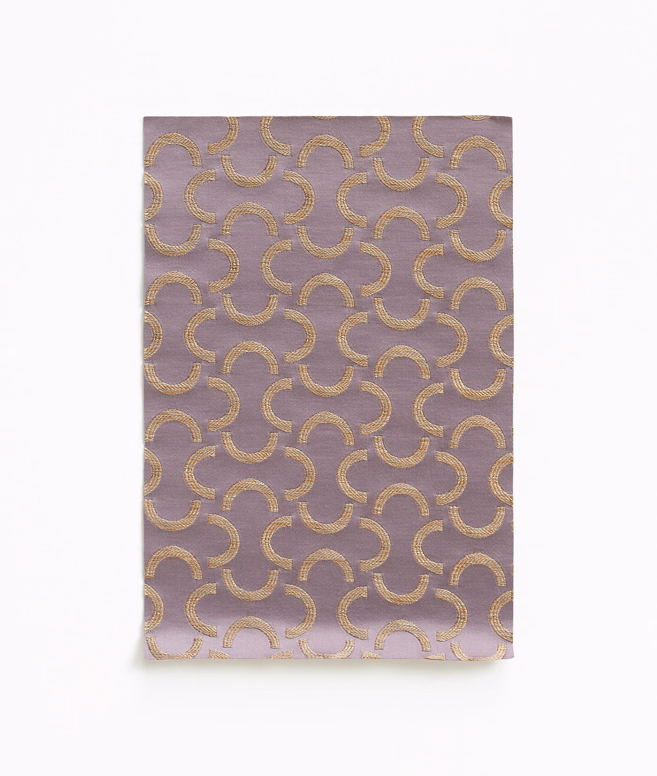 Mauve-lilac satin swatch with repeating brushed-gold interlocking crescent motifs