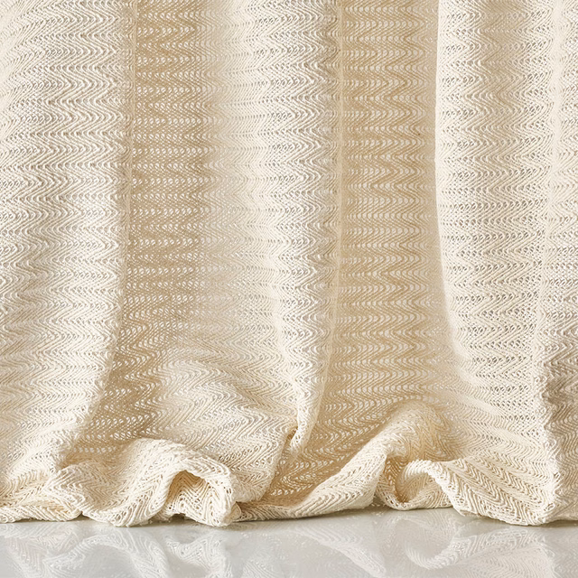 Warm ivory sheer with fine looping wave texture gathered into soft folds