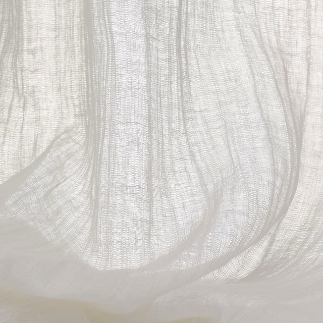Pale ivory sheer fabric with open vertical weave gathered into translucent folds