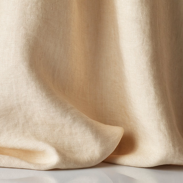 Sheer blush-beige textile pooling in soft folds, with a fine linen-like weave
