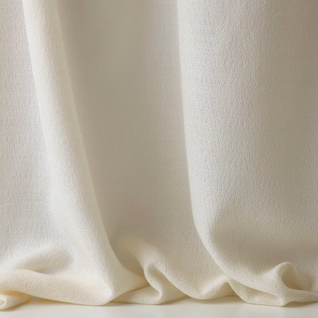 Warm ivory sheer fabric with fine pebbled texture falling into soft fluid folds