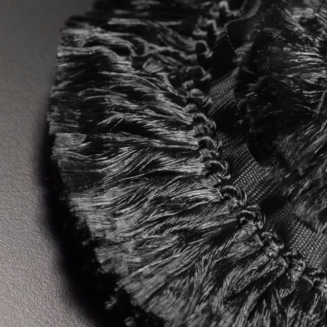 Glossy black fringe with braided trim and dense, feathered texture