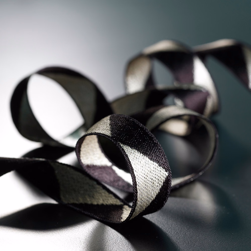 Looped black, ivory and muted plum braid showing a fine woven texture