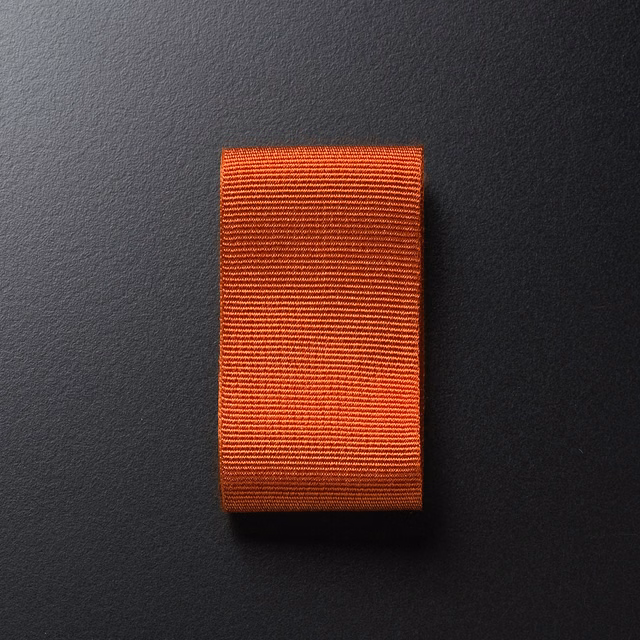 Burnt-orange textile swatch with fine, densely spaced horizontal ribs and subtle red-brown depth