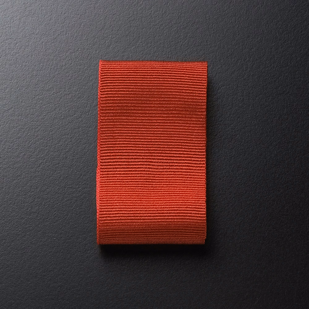 Warm brick-red Dedar textile swatch with fine horizontal ribbed texture