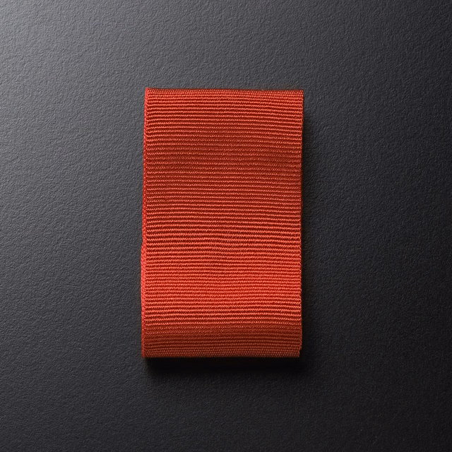 Warm brick-red Dedar textile swatch with fine horizontal ribbed texture