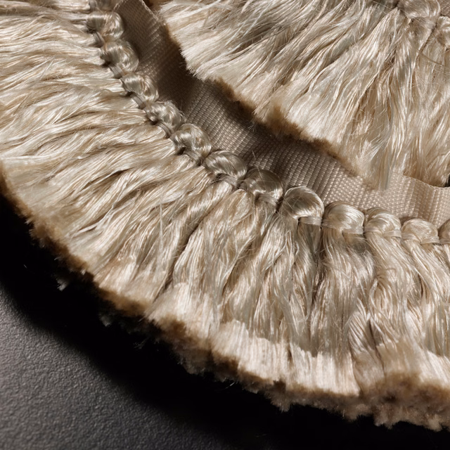 Pale champagne fringe with looped edging, silky strands and taupe shadowed texture