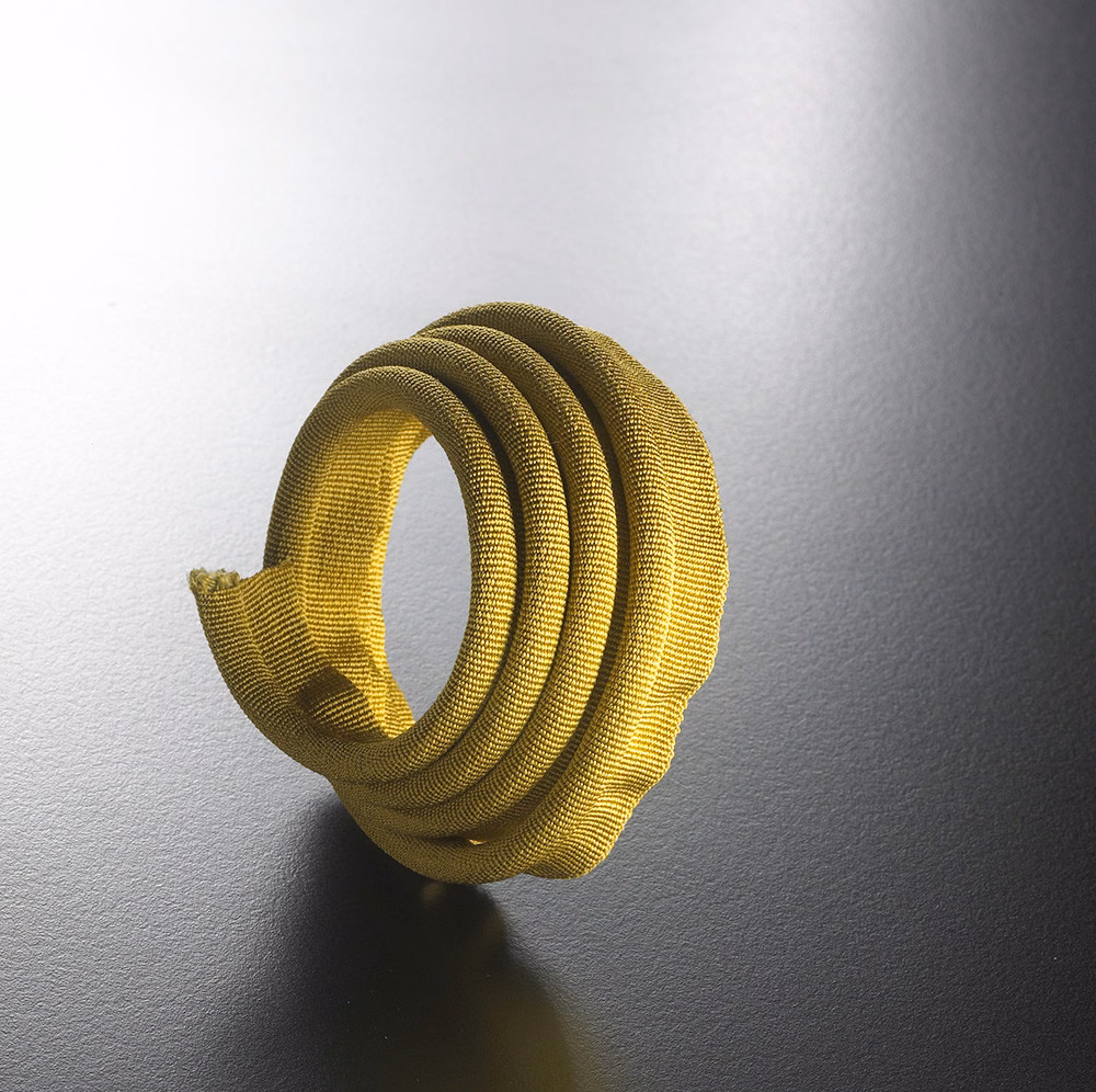 Coiled mustard-olive gold lipcord with a closely ribbed tubular textile surface