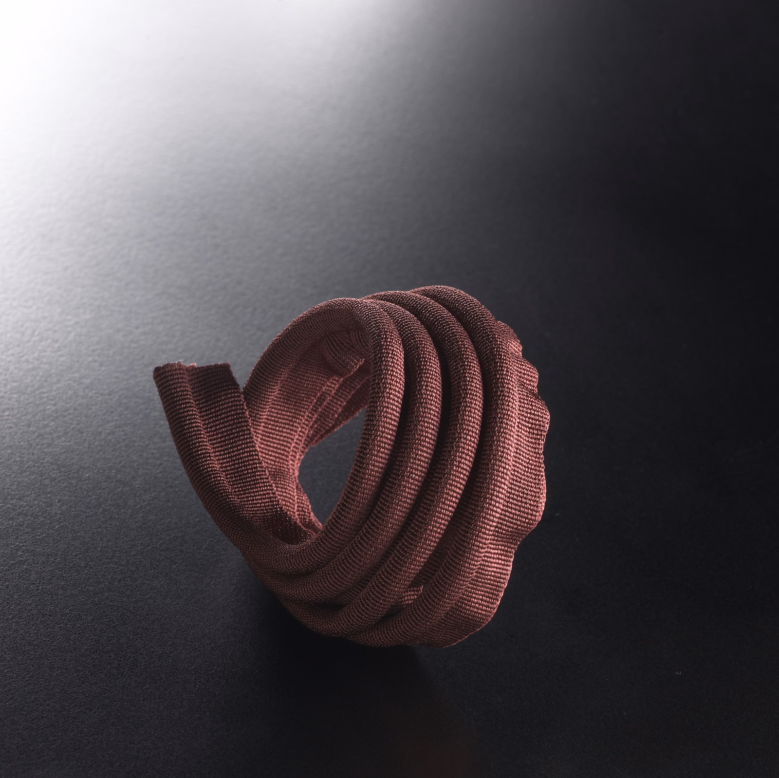 Deep plum ribbed lipcord looped into a sculptural rounded coil