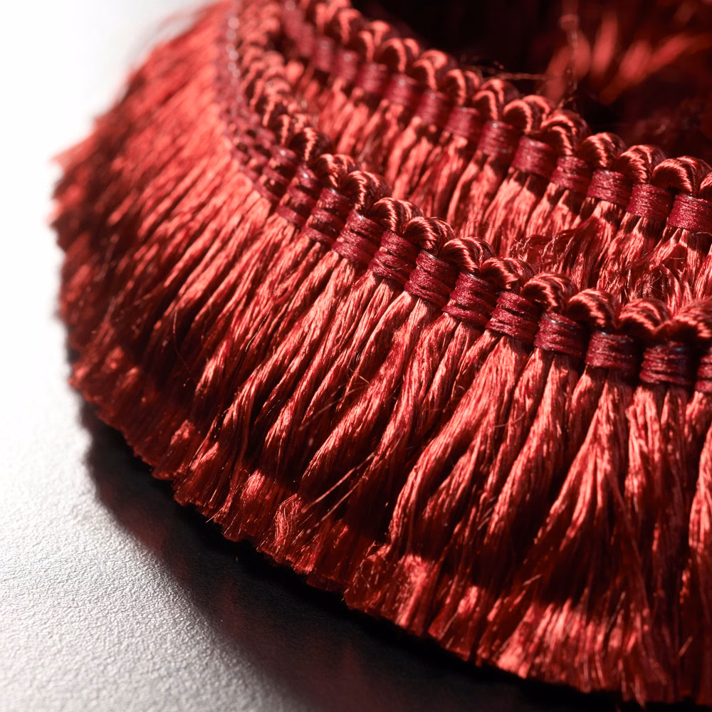 Close-up of glossy Bordeaux-red fringe with braided header and deep wine shadows