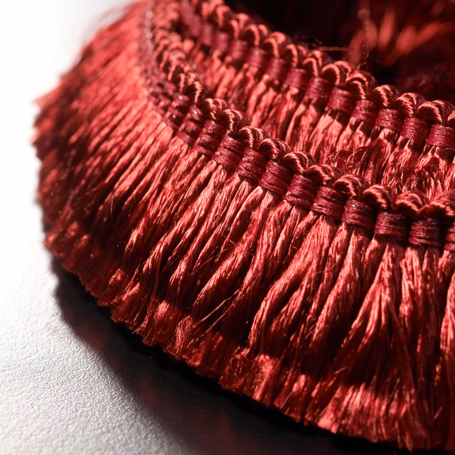 Close-up of glossy Bordeaux-red fringe with braided header and deep wine shadows
