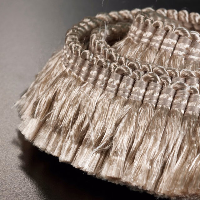 Warm cream looped trim with glossy bands and dense, flowing fringe