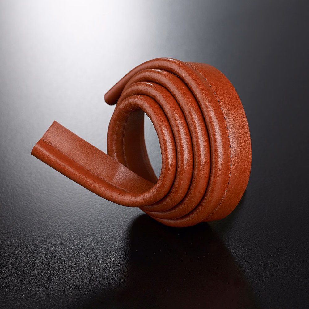 Warm russet-brown lipcord coiled into rounded loops on a black surface