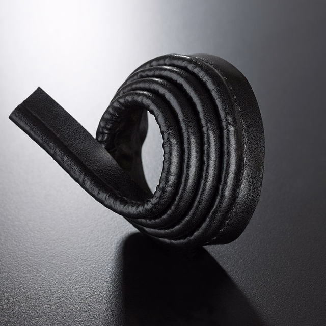 Black lipcord trim curled into concentric ridges, showing pebbled texture and glossy highlights