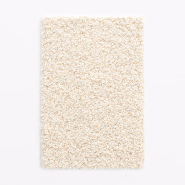 Warm ivory bouclé swatch showing dense, irregular loops and a softly nubby surface