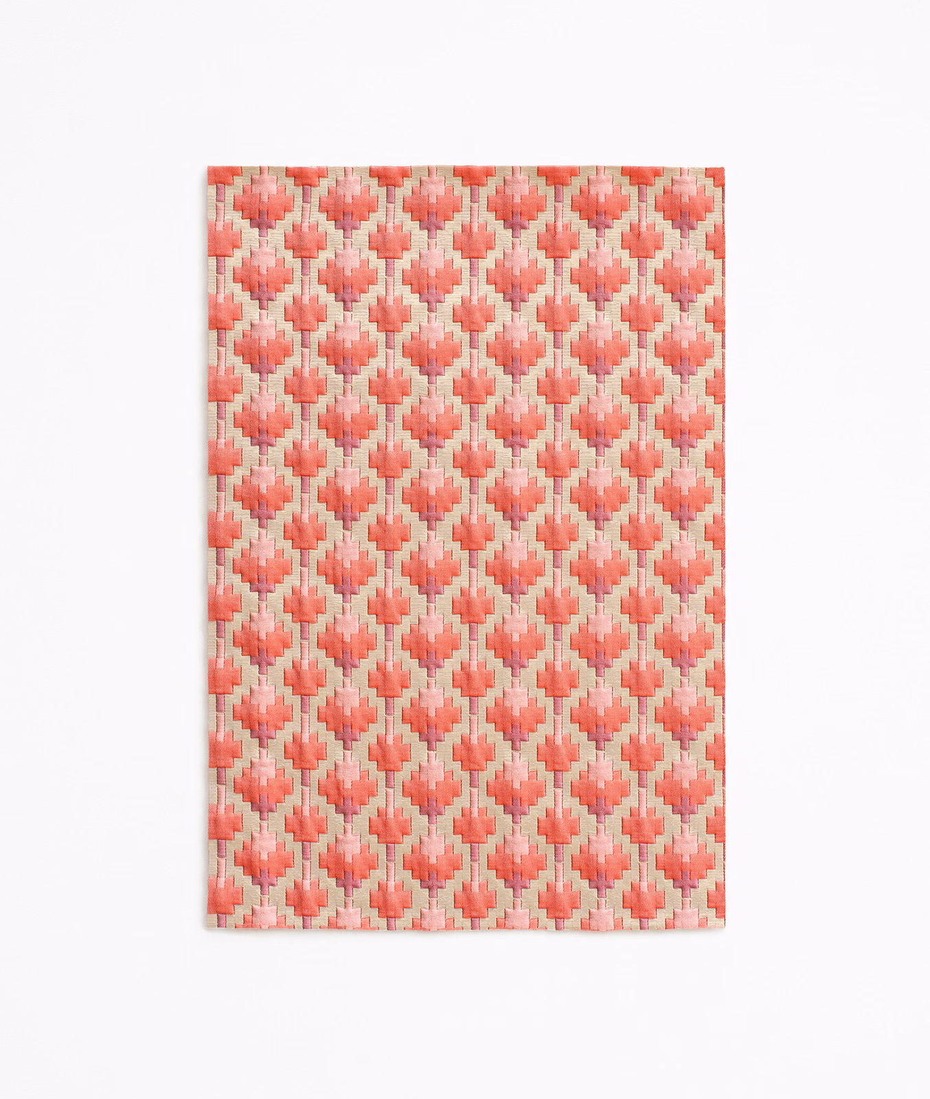Warm coral-red woven fabric with blush diamonds and pale cream vertical accents