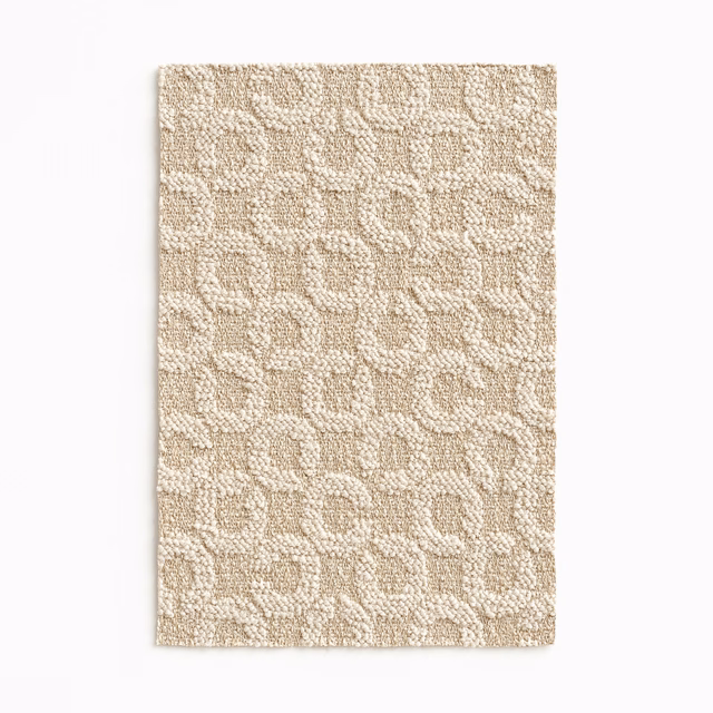 Warm oat-beige woven swatch with raised pebble-like motifs and softly flecked texture