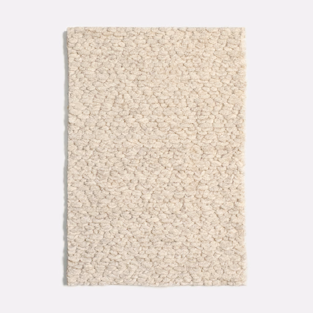 Pale cream bouclé upholstery swatch with dense irregular loops and softly flecked texture