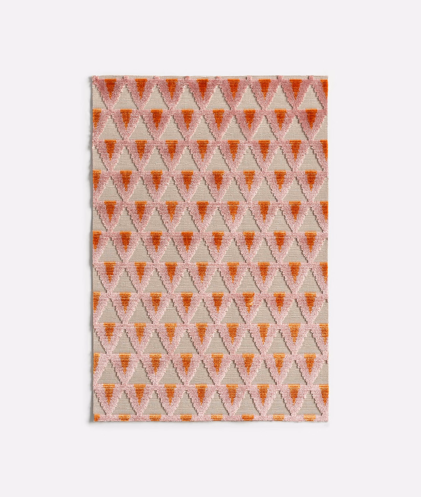 Warm coral and blush velvet swatch with repeating small hourglass motifs and woven texture