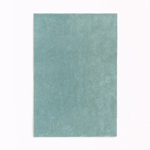 Close-up of softly mottled cool celadon green velvet with a gentle plush sheen