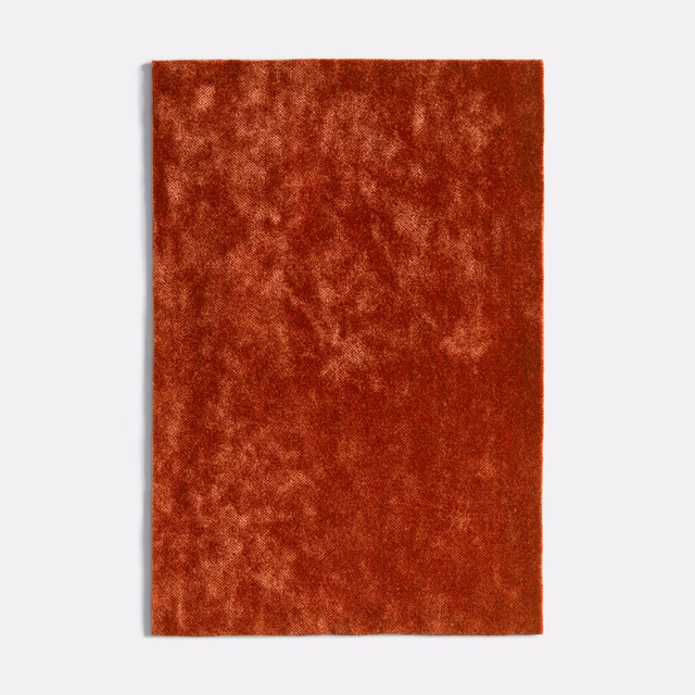 Burnt-coral velvet swatch with cloudy rust mottling and a plush light-catching pile