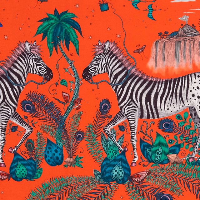 Coral-red fabric with zebras, palms, peacocks and layered botanical motifs