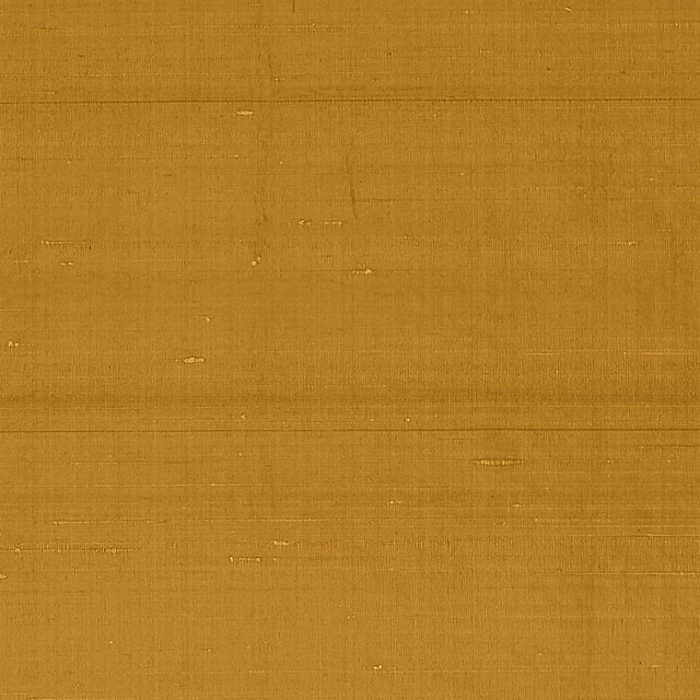 Warm amber plain weave with fine slubs and scattered lighter flecks