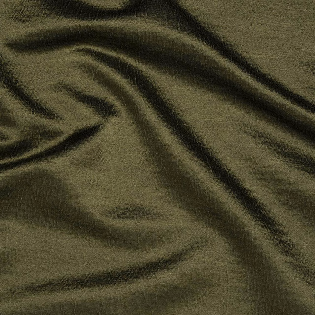 Folded olive-green woven fabric with dark shadowed creases and subtle slub texture