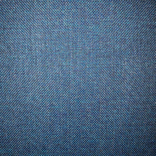Close-up of a textured teal woven fabric with blue and charcoal flecks