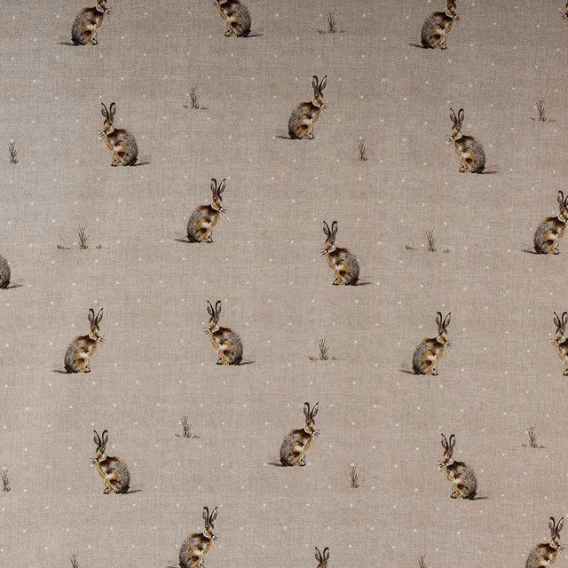 Beige cotton fabric with scattered hare motifs and tiny grass sprigs