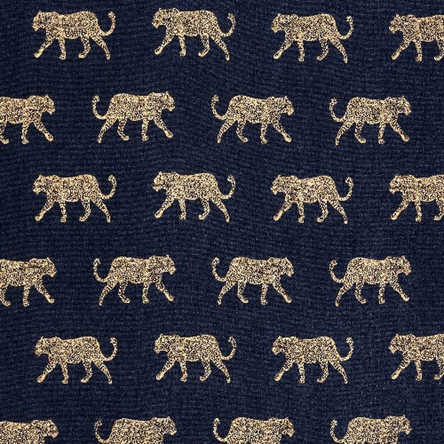Dark indigo fabric with small gold leopard motifs and a visible woven texture.