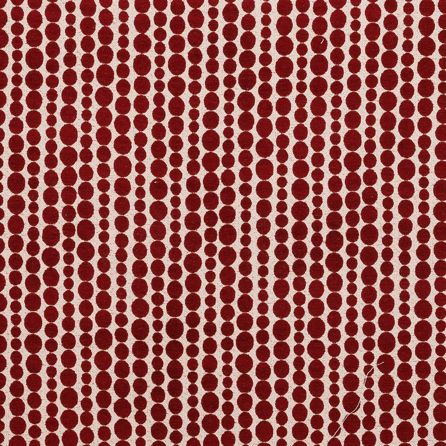 Red polka-dot patterned fabric swatch on a pale ground, with woven texture
