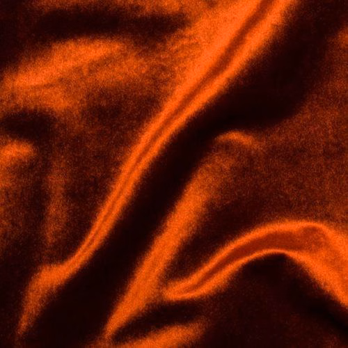 Close-up of deep burnt orange velvet fabric with glossy folds