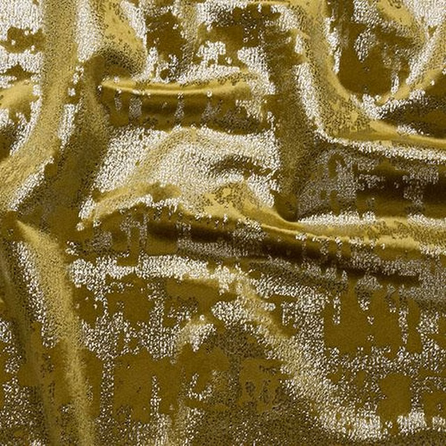 Close-up of a glossy ochre-gold abstract fabric with crumpled texture and light-catching highlights
