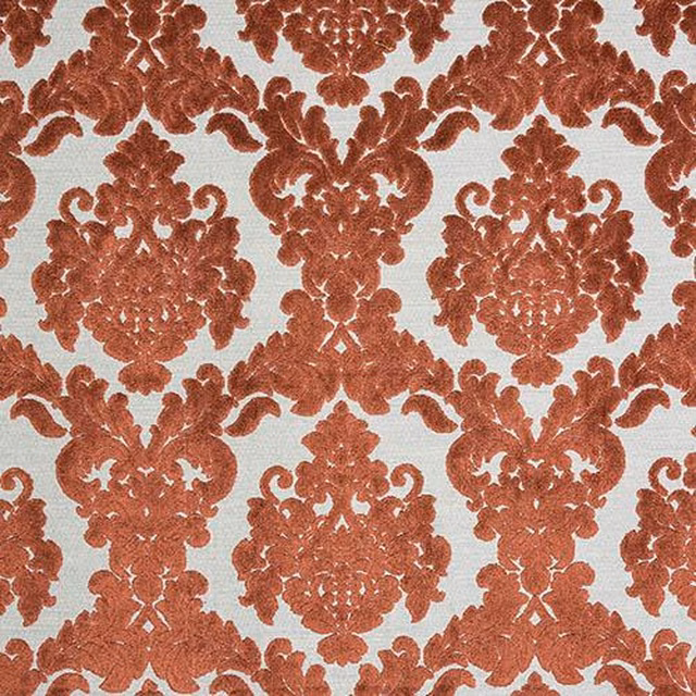 Burnt orange damask fabric on a pale ground with textured woven surface