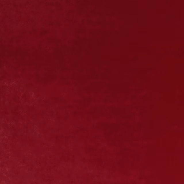 Deep ruby red velvet with subtle directional pile and soft light variation