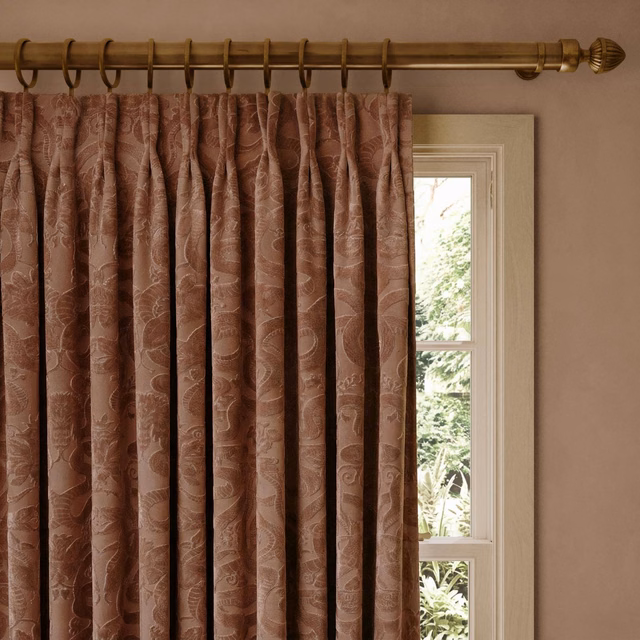 Dusky pink velvet curtains with tonal winding motifs in deep window pleats