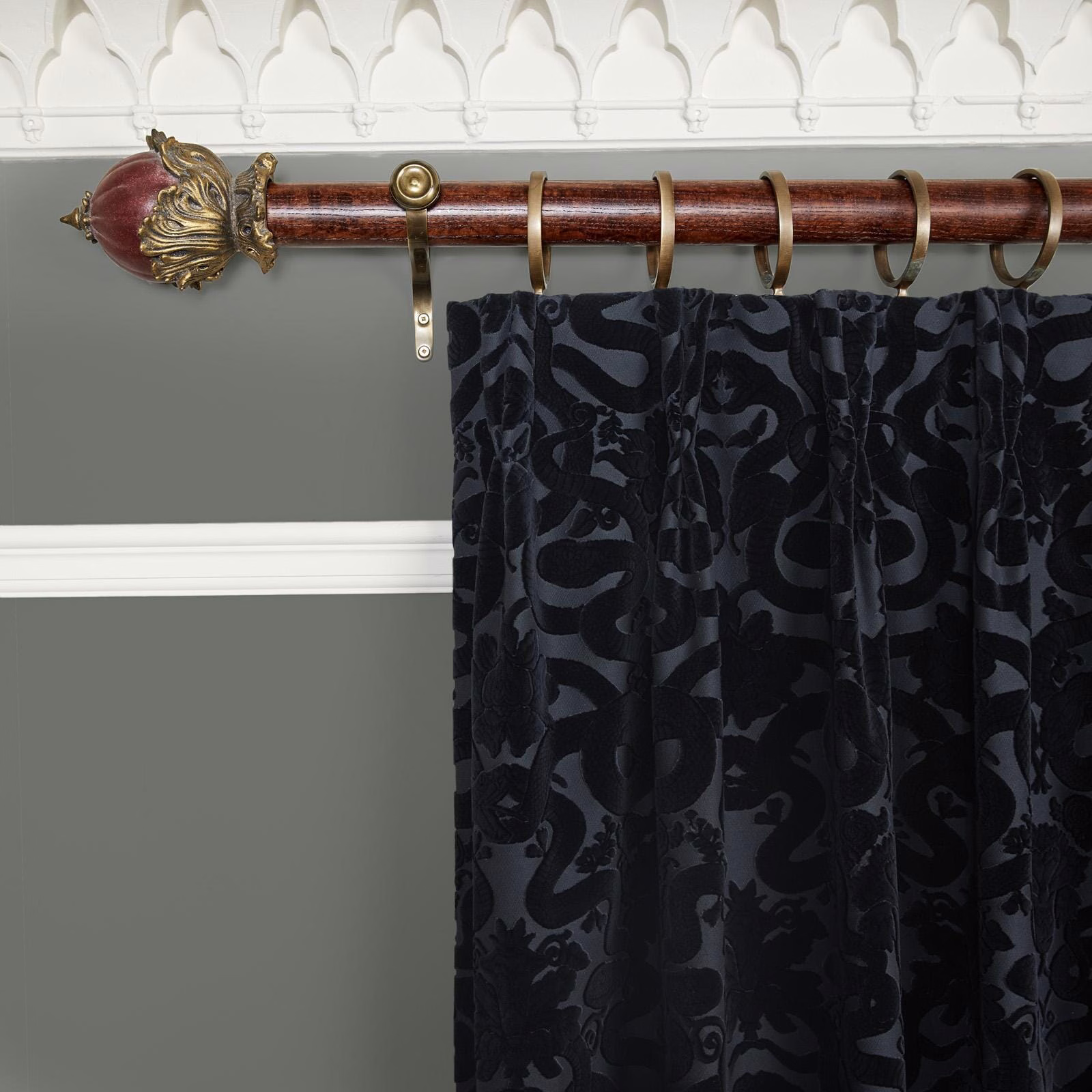 Near-black velvet curtain with tonal scrolling foliage and deep gathered folds