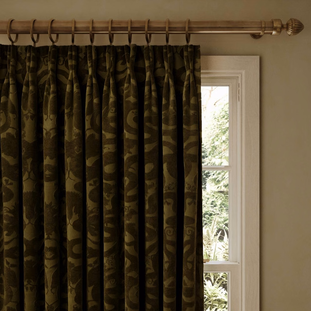 Deep olive velvet curtains with tonal serpentine motifs in strong vertical pleats