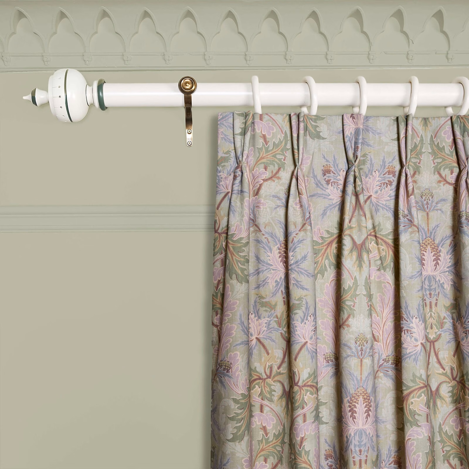 Muted apple-green curtain with pink, lilac and blue botanical motifs in gathered folds