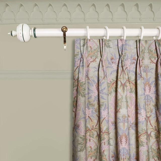 Muted apple-green curtain with pink, lilac and blue botanical motifs in gathered folds