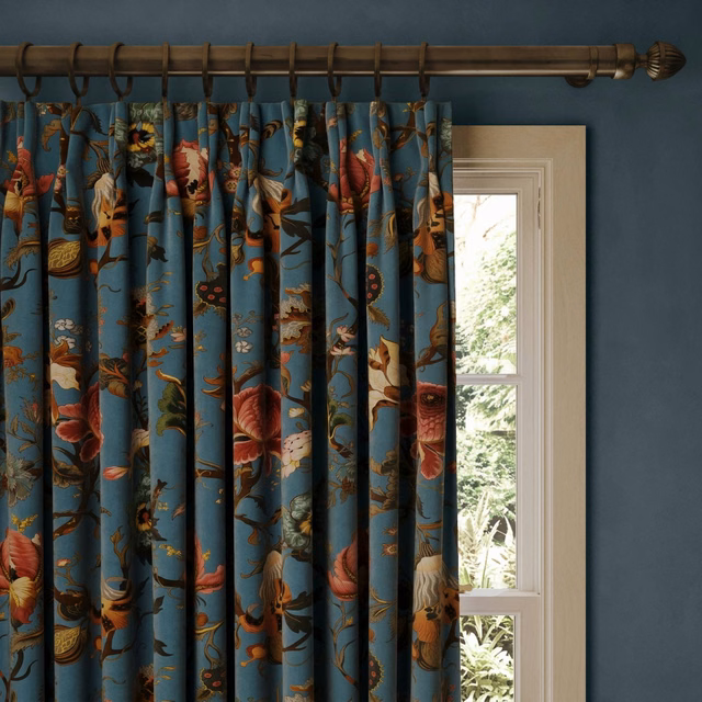 Deep azure velvet curtains with coral flowers, foliage and bird motifs beside a window
