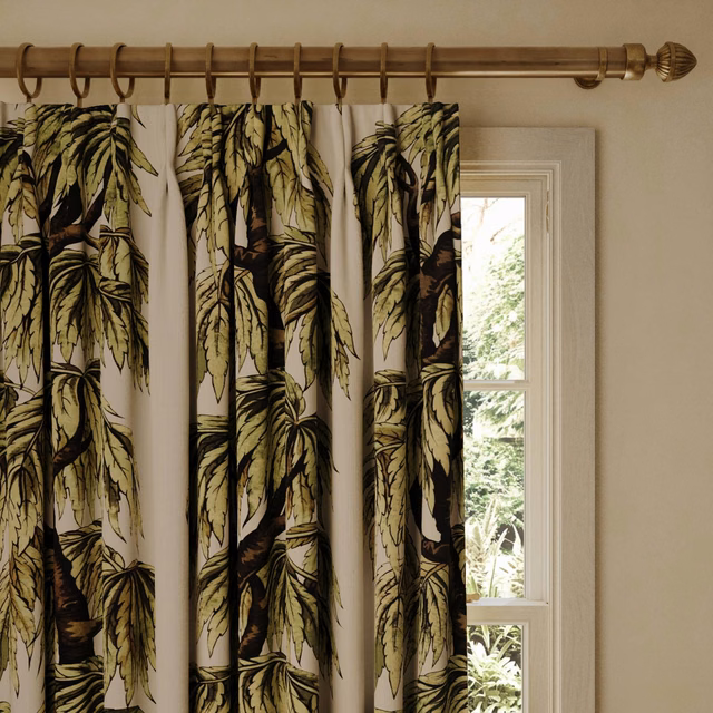 Papyrus curtains with oversized olive botanical leaves beside a sunlit window